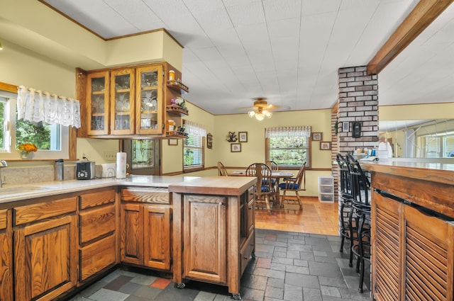 3914 135th Ave, Hersey, MI 49639 - kitchen featuring a peninsula, brown cabinets, a ceiling fan, and glass insert cabinets