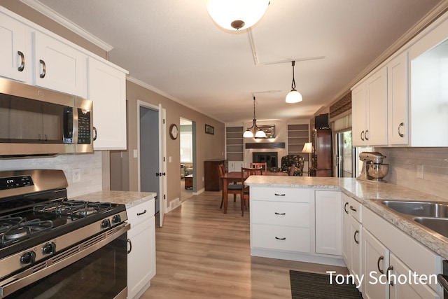 8179 Mellowwood Dr, Jenison, MI 49428 - kitchen featuring stainless steel appliances, a peninsula, white cabinetry, and ornamental molding