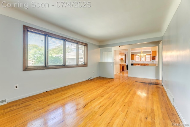 8571 Linda St, Warren, MI 48093 - unfurnished living room with a chandelier and light wood finished floors