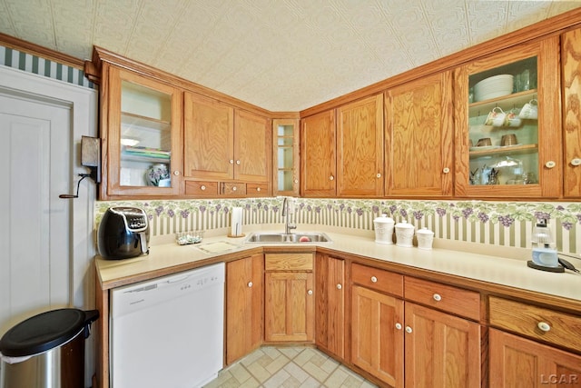 216 Budlong St, Adrian, MI 49221 - kitchen featuring white dishwasher, light countertops, glass insert cabinets, brown cabinetry, and wallpapered walls