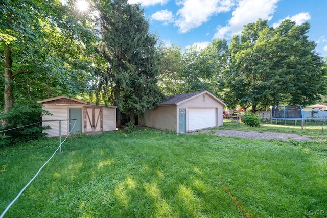 216 Budlong St, Adrian, MI 49221 - view of yard with a trampoline, an outdoor structure, and a detached garage