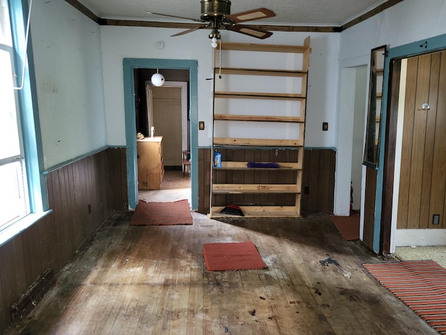 233 2nd Ave, Manistee, MI 49660 - empty room with hardwood / wood-style flooring, crown molding, ceiling fan, wainscoting, and wooden walls