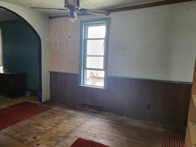 233 2nd Ave, Manistee, MI 49660 - unfurnished room with a ceiling fan, hardwood / wood-style flooring, a wainscoted wall, arched walkways, and wood walls