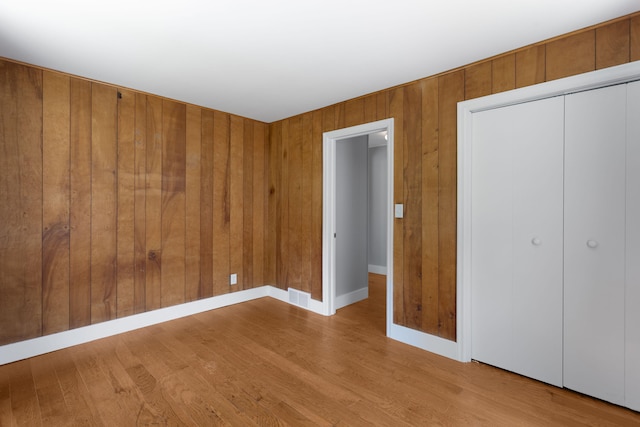 1200 Orchard Ave, Saint Joseph, MI 49085 - unfurnished bedroom featuring wood finished floors, a closet, and wood walls