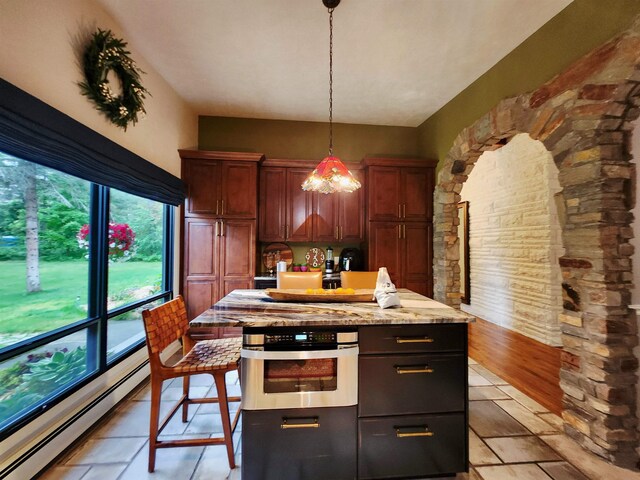 241 Dale St, Grayling, MI 49738 - kitchen featuring a baseboard heating unit, stainless steel oven, decorative light fixtures, a center island, and light stone countertops