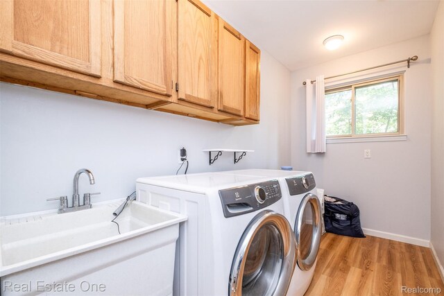 4079 Cumberland Ct, Commerce Twp, MI 48390 - laundry area featuring separate washer and dryer, cabinet space, and light wood-style flooring