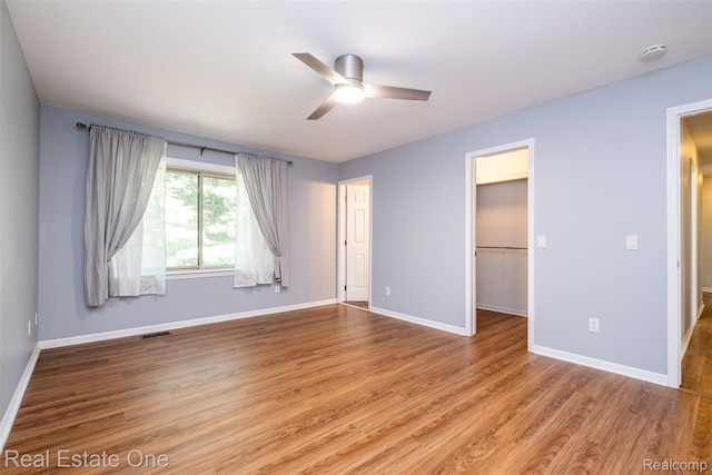 4079 Cumberland Ct, Commerce Twp, MI 48390 - unfurnished bedroom with wood finished floors, a walk in closet, and a ceiling fan