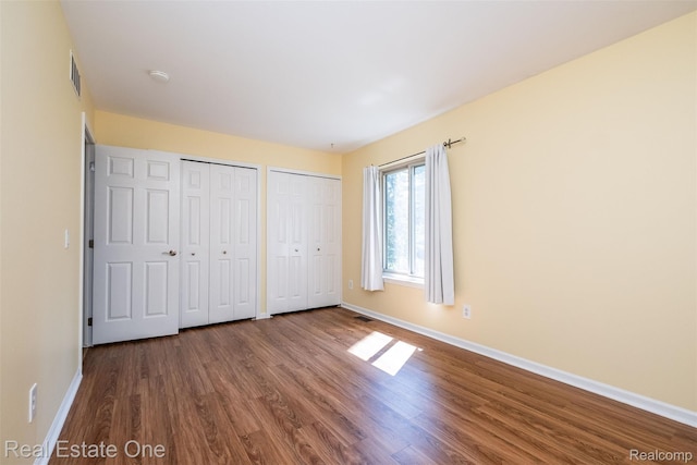 4079 Cumberland Ct, Commerce Twp, MI 48390 - unfurnished bedroom featuring two closets and wood finished floors