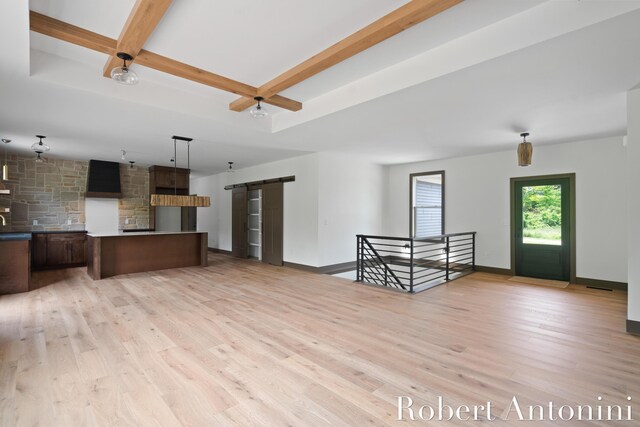 6691 Egan Ave SE, Caledonia, MI 49316 - kitchen with a barn door, light wood-style flooring, beam ceiling, hanging light fixtures, and open floor plan