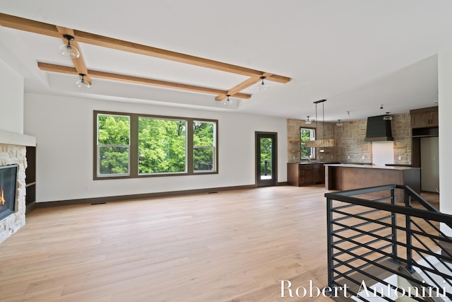 6691 Egan Ave SE, Caledonia, MI 49316 - unfurnished living room with a stone fireplace, beam ceiling, and light wood-style flooring