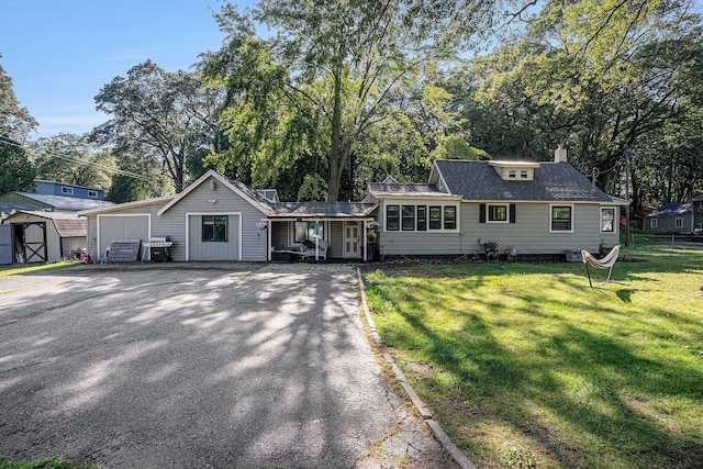 2559 Miner Ave, Muskegon, MI 49441 - view of front facade featuring a shed, a front yard, view of wooded area, a chimney, and a shingled roof