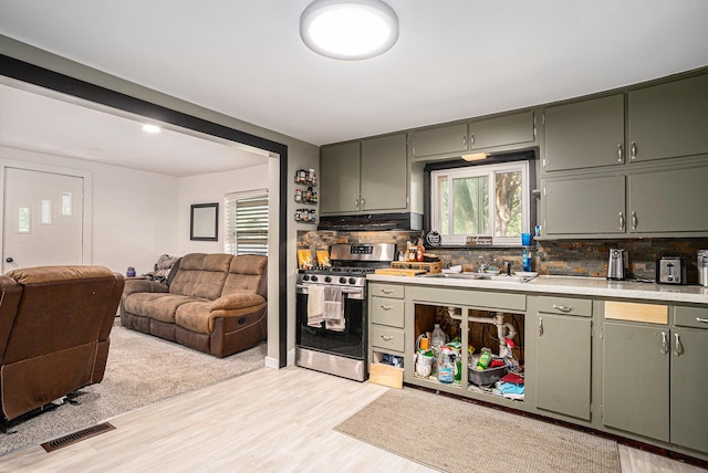 2559 Miner Ave, Muskegon, MI 49441 - kitchen with stainless steel range with gas stovetop, under cabinet range hood, backsplash, light countertops, and light wood finished floors