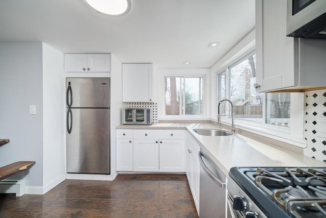 17016 6th St, Wellston, MI 49689 - kitchen with appliances with stainless steel finishes, dark wood-style flooring, light countertops, white cabinetry, and backsplash