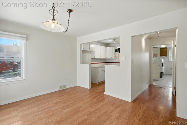 420 Wellsboro St, Walled Lake, MI 48390 - kitchen with light wood finished floors, separate washer and dryer, light countertops, pendant lighting, and white cabinets