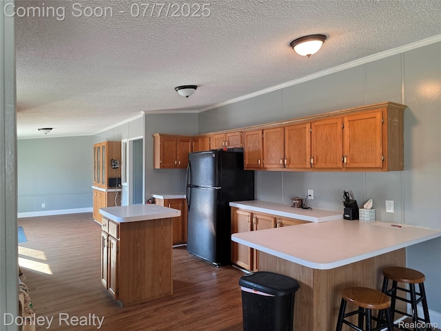 4605 Pleasant St, Clifford, MI 48727 - kitchen with freestanding refrigerator, ornamental molding, a textured ceiling, a peninsula, and dark wood-type flooring