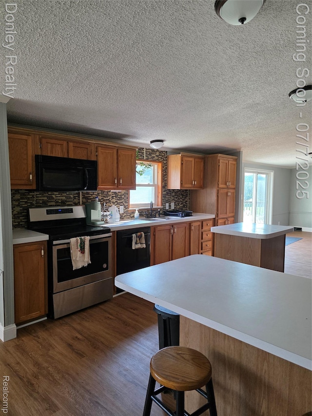 4605 Pleasant St, Clifford, MI 48727 - kitchen featuring black appliances, decorative backsplash, light countertops, dark wood-style flooring, and a textured ceiling