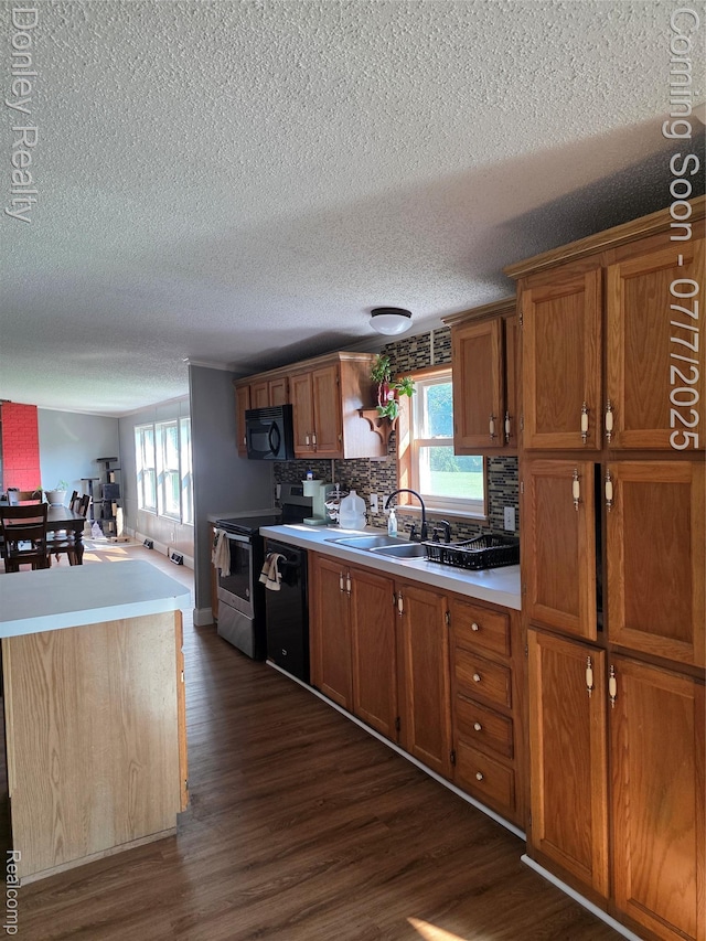 4605 Pleasant St, Clifford, MI 48727 - kitchen with black appliances, dark wood-type flooring, brown cabinetry, a textured ceiling, and healthy amount of natural light