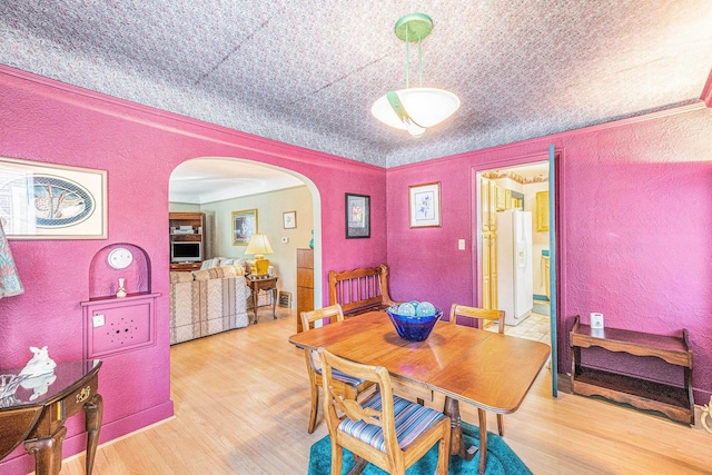 927 Kensington Ave, Flint, MI 48503 - dining room with a textured wall, arched walkways, wood finished floors, and crown molding