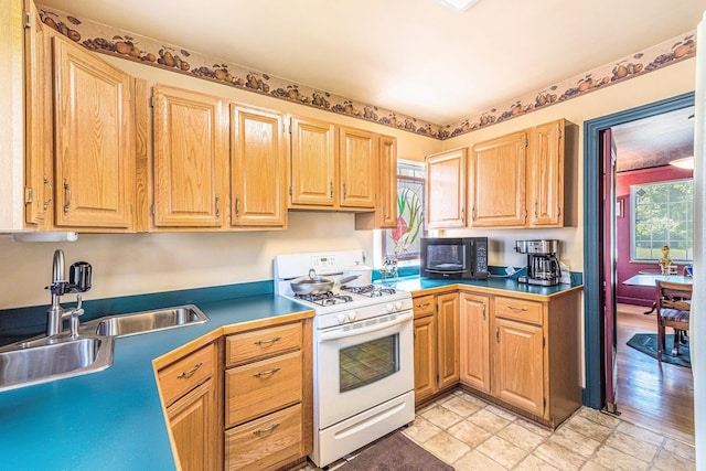 927 Kensington Ave, Flint, MI 48503 - kitchen with white gas range oven, plenty of natural light, black microwave, and light brown cabinetry
