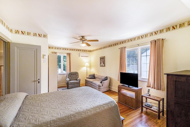 927 Kensington Ave, Flint, MI 48503 - bedroom with an AC wall unit, multiple windows, wood finished floors, and a ceiling fan