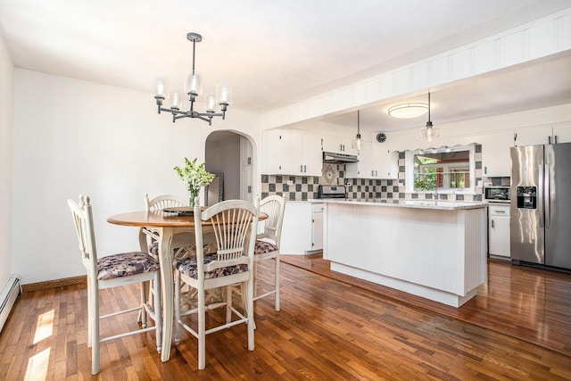 14814 Stone Jug Rd, Battle Creek, MI 49015 - dining area with arched walkways, a chandelier, dark wood-type flooring, and a baseboard radiator
