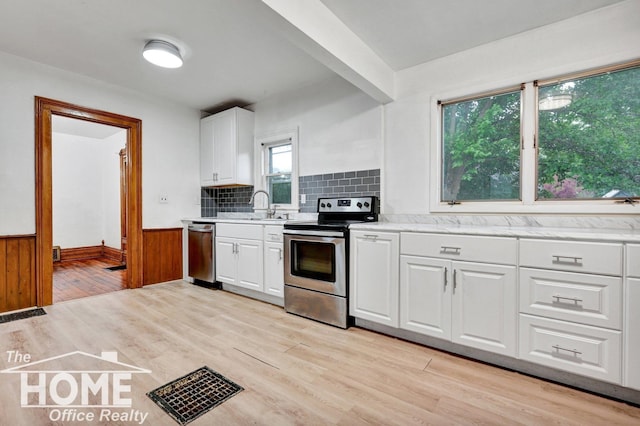 1114 Lynn St, Owosso, MI 48867 - kitchen with appliances with stainless steel finishes, light wood-type flooring, a wainscoted wall, white cabinetry, and decorative backsplash