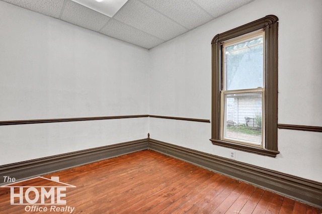 1114 Lynn St, Owosso, MI 48867 - empty room with a drop ceiling, plenty of natural light, and hardwood / wood-style flooring