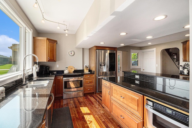 9991 Kaiser Rd, Saline, MI 48176 - kitchen featuring appliances with stainless steel finishes, dark wood-type flooring, arched walkways, dark stone counters, and recessed lighting