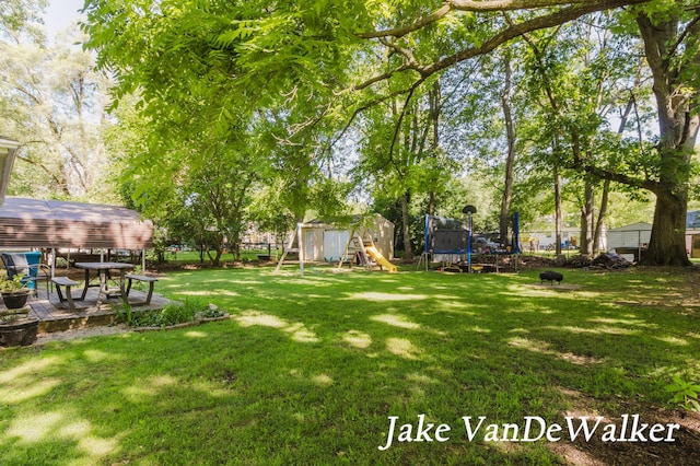 2338 Edgewood Dr, Kalamazoo, MI 49008 - fenced backyard with a trampoline, a playground, a storage unit, and a wooden deck