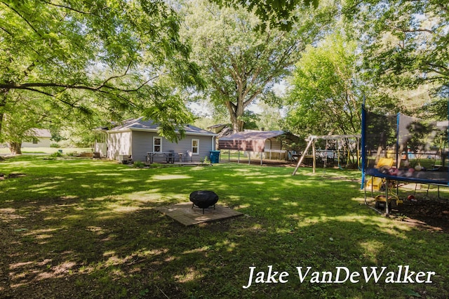 2338 Edgewood Dr, Kalamazoo, MI 49008 - fenced backyard with a trampoline, a playground, and an outdoor fire pit