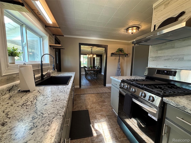 1295 S M 33, West Branch, MI 48661 - kitchen with stainless steel gas range, wall chimney range hood, a chandelier, light stone counters, and gray cabinets