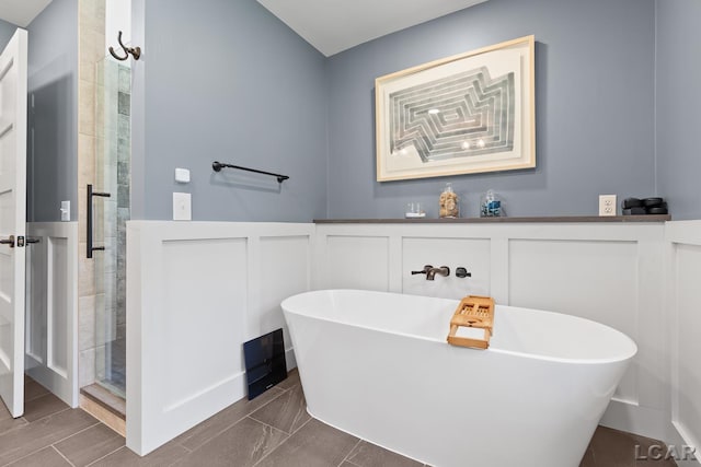 144 N Scott St, Adrian, MI 49221 - bathroom with a soaking tub, a stall shower, a wainscoted wall, and a decorative wall