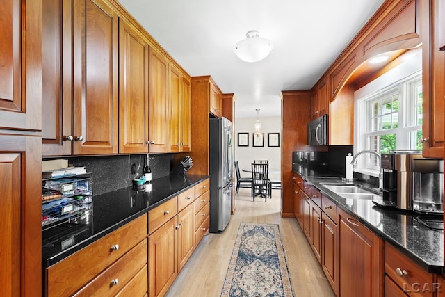 144 N Scott St, Adrian, MI 49221 - kitchen with appliances with stainless steel finishes, light wood-type flooring, brown cabinetry, dark stone counters, and tasteful backsplash