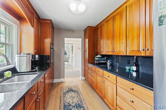 144 N Scott St, Adrian, MI 49221 - kitchen featuring light wood-style floors, backsplash, dark stone counters, and brown cabinetry