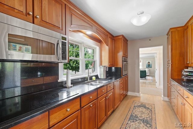 144 N Scott St, Adrian, MI 49221 - kitchen with appliances with stainless steel finishes, brown cabinetry, light wood-style flooring, and dark stone counters