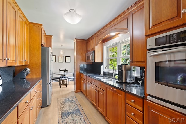 144 N Scott St, Adrian, MI 49221 - kitchen with stainless steel appliances, light wood finished floors, brown cabinets, and dark stone countertops