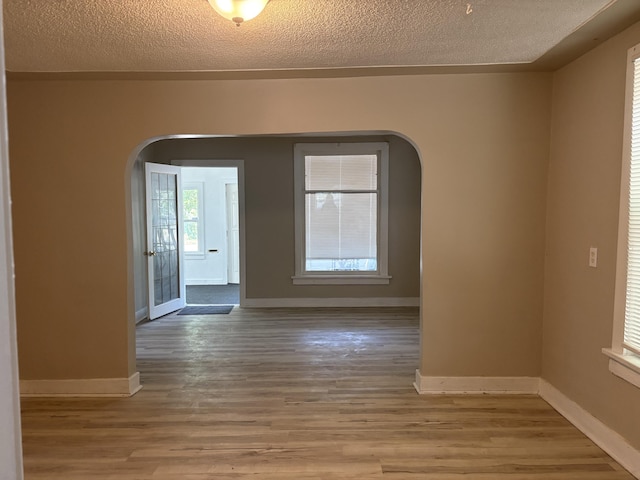 2233 Mc Ilwraith St, Muskegon Heights, MI 49444 - unfurnished room with arched walkways, wood finished floors, and a textured ceiling