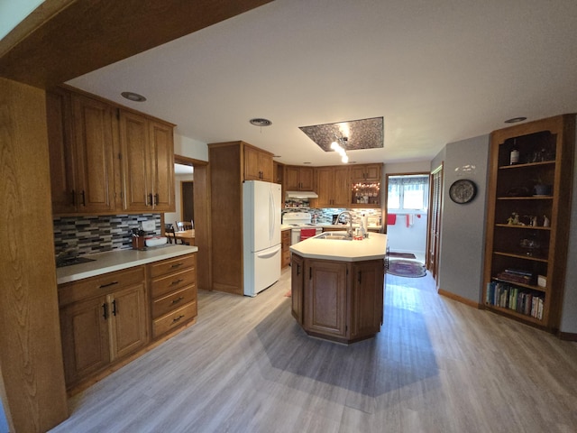971 Weaver Rd, Bronson, MI 49028 - kitchen featuring freestanding refrigerator, light wood-style floors, tasteful backsplash, light countertops, and a center island with sink