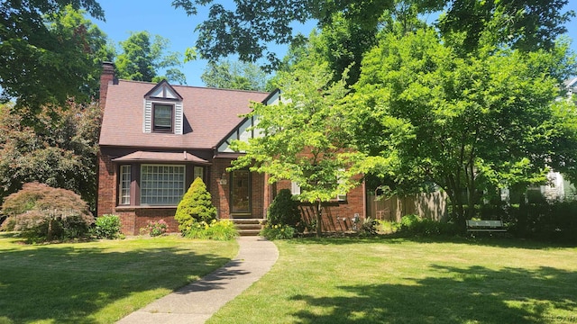 401 Budlong St, Adrian, MI 49221 - tudor house featuring a front lawn, a chimney, and brick siding