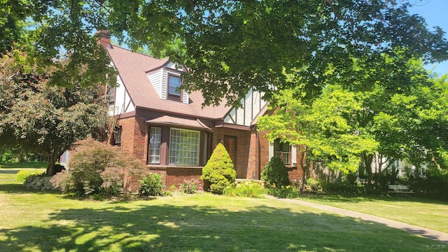 401 Budlong St, Adrian, MI 49221 - tudor house featuring brick siding, a front lawn, and a chimney