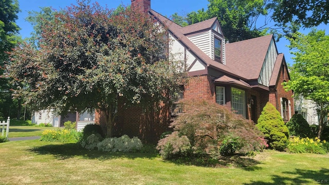 401 Budlong St, Adrian, MI 49221 - view of home's exterior featuring a yard, brick siding, a chimney, and a garage