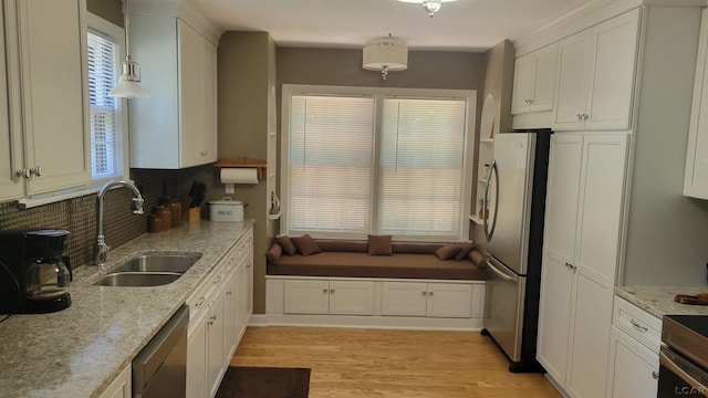 401 Budlong St, Adrian, MI 49221 - kitchen featuring stainless steel appliances, white cabinets, tasteful backsplash, light wood finished floors, and hanging light fixtures