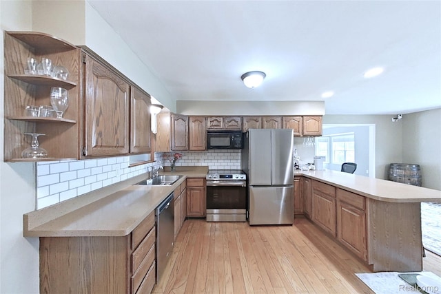 9100 Mayfred Dr, Pinckney, MI 48169 - kitchen featuring appliances with stainless steel finishes, a peninsula, light wood-style flooring, tasteful backsplash, and light countertops