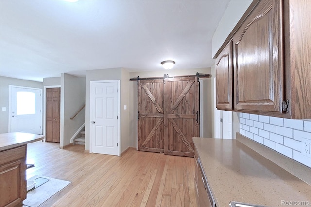 9100 Mayfred Dr, Pinckney, MI 48169 - kitchen featuring backsplash, light wood-style flooring, a barn door, and light countertops