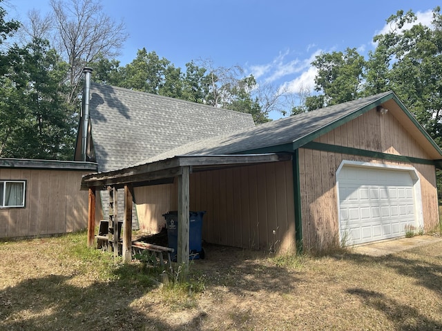 3423 S James Rd, Baldwin, MI 49304 - view of home's exterior with a shingled roof, a garage, and an outbuilding