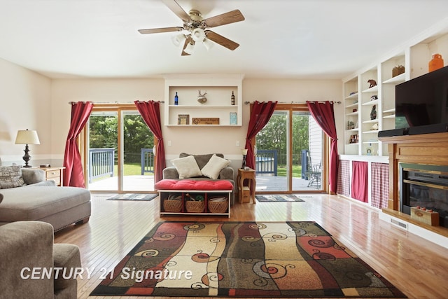 3405 S Miller Rd, Saginaw, MI 48609 - living area featuring healthy amount of natural light, wood finished floors, a glass covered fireplace, and a ceiling fan