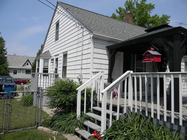 103 S Staffon St, Ludington, MI 49431 - view of front of house with a shingled roof, a gate, a chimney, and a deck