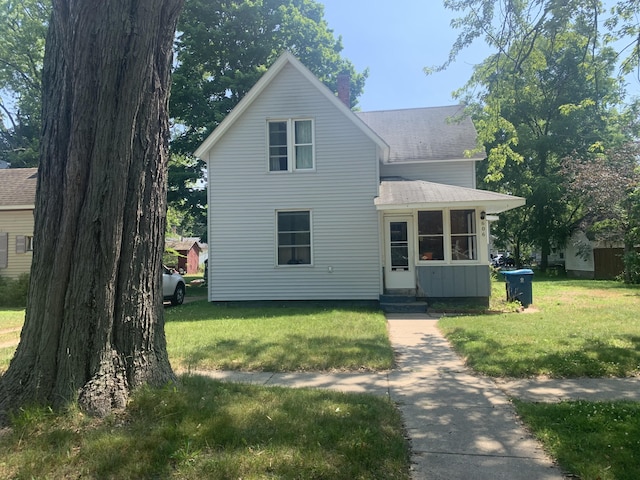 606 N Harrison St, Ludington, MI 49431 - traditional home with a front yard, entry steps, roof with shingles, and a chimney