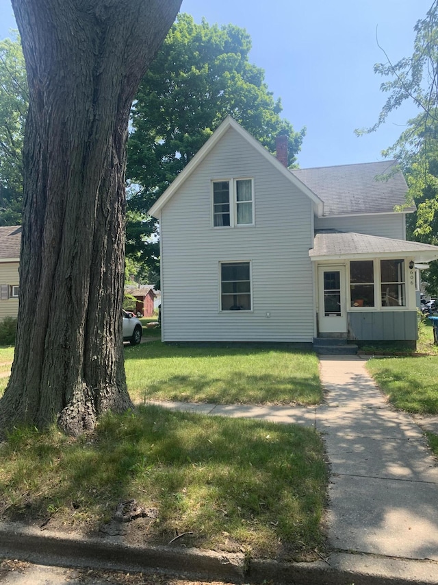 606 N Harrison St, Ludington, MI 49431 - traditional home with a chimney, a front lawn, and entry steps