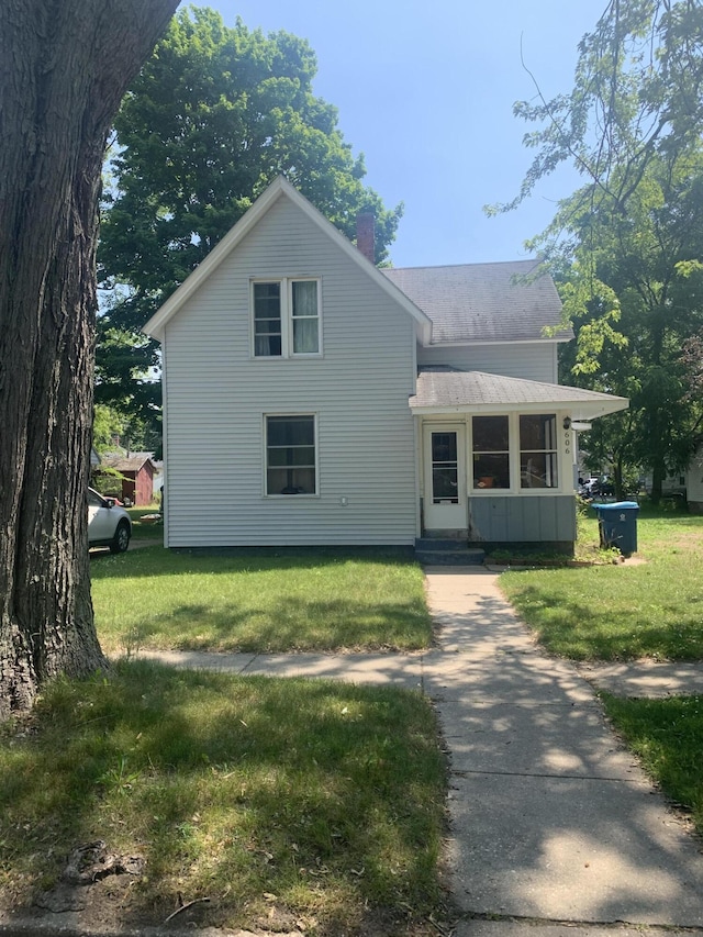 606 N Harrison St, Ludington, MI 49431 - traditional home featuring a chimney, a front yard, board and batten siding, and roof with shingles